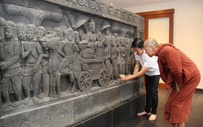 Bro.Tan showing Ven. Aggacitta the intricate details of the 'Procession of Mayadevi' stone relief.
