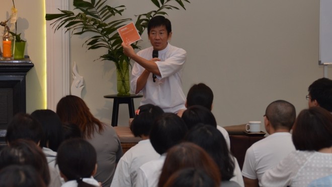 Bro. Tan reminds the congregation to keep a log of their practice in the booklet specially printed for the Gimhana retreat.